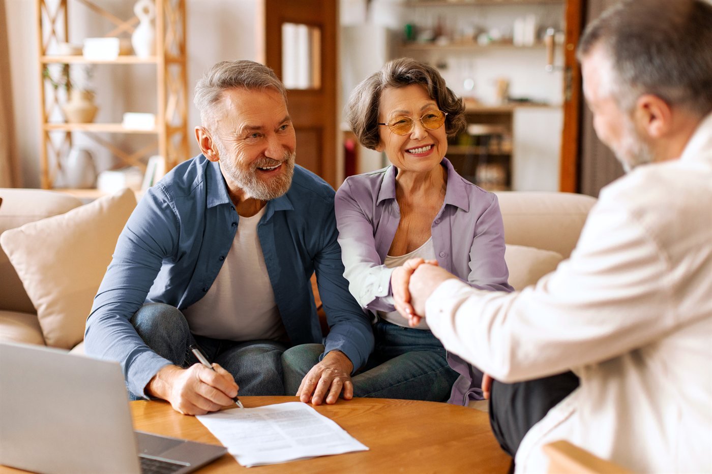 A happy couple shaking hands with their financial advisor at home
